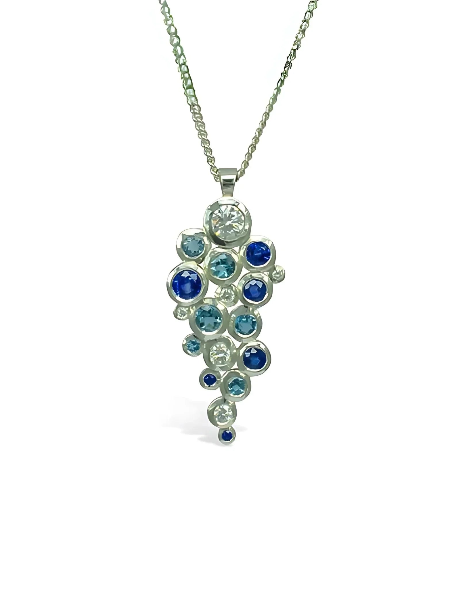 Silver pendant necklace with clustered blue sapphires and diamonds on a white background