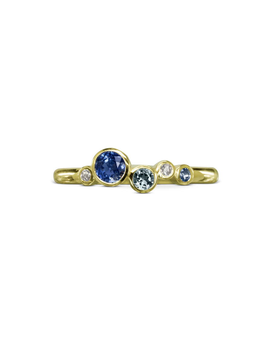 Gold engagement ring with offset blue sapphires and diamonds in organic, modern design