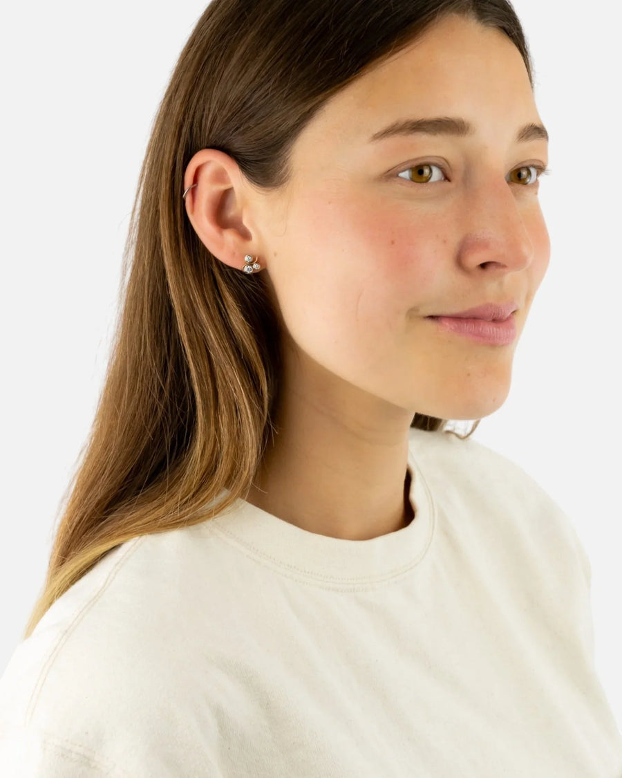 Woman wearing yellow gold diamond stud earrings with water bubble design