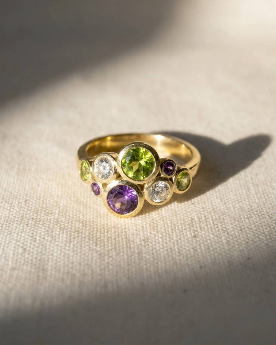 9ct yellow gold ring with oval and round peridot, amethyst, and white gemstones.