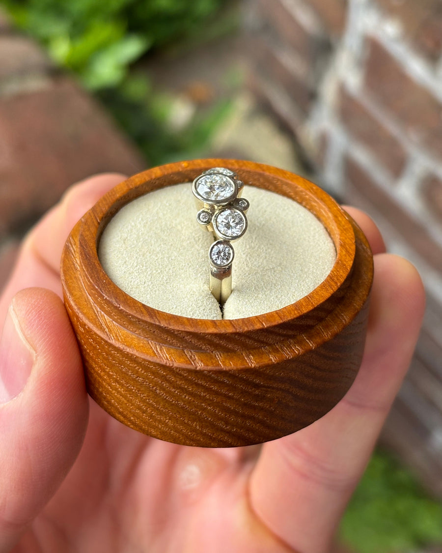 Silver engagement ring with round lab-grown diamonds in a bubble cluster setting inside a wooden box.