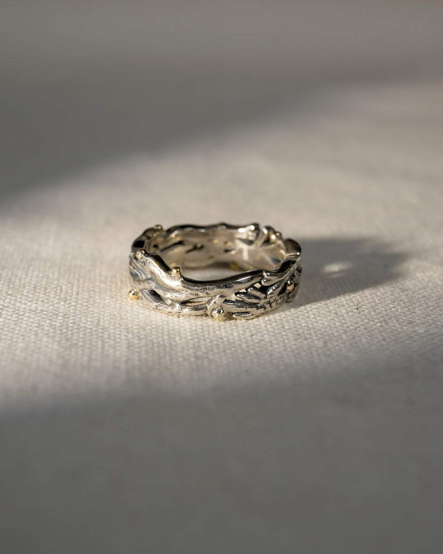 Textured handmade wedding ring with organic branch design in silver and gold on linen