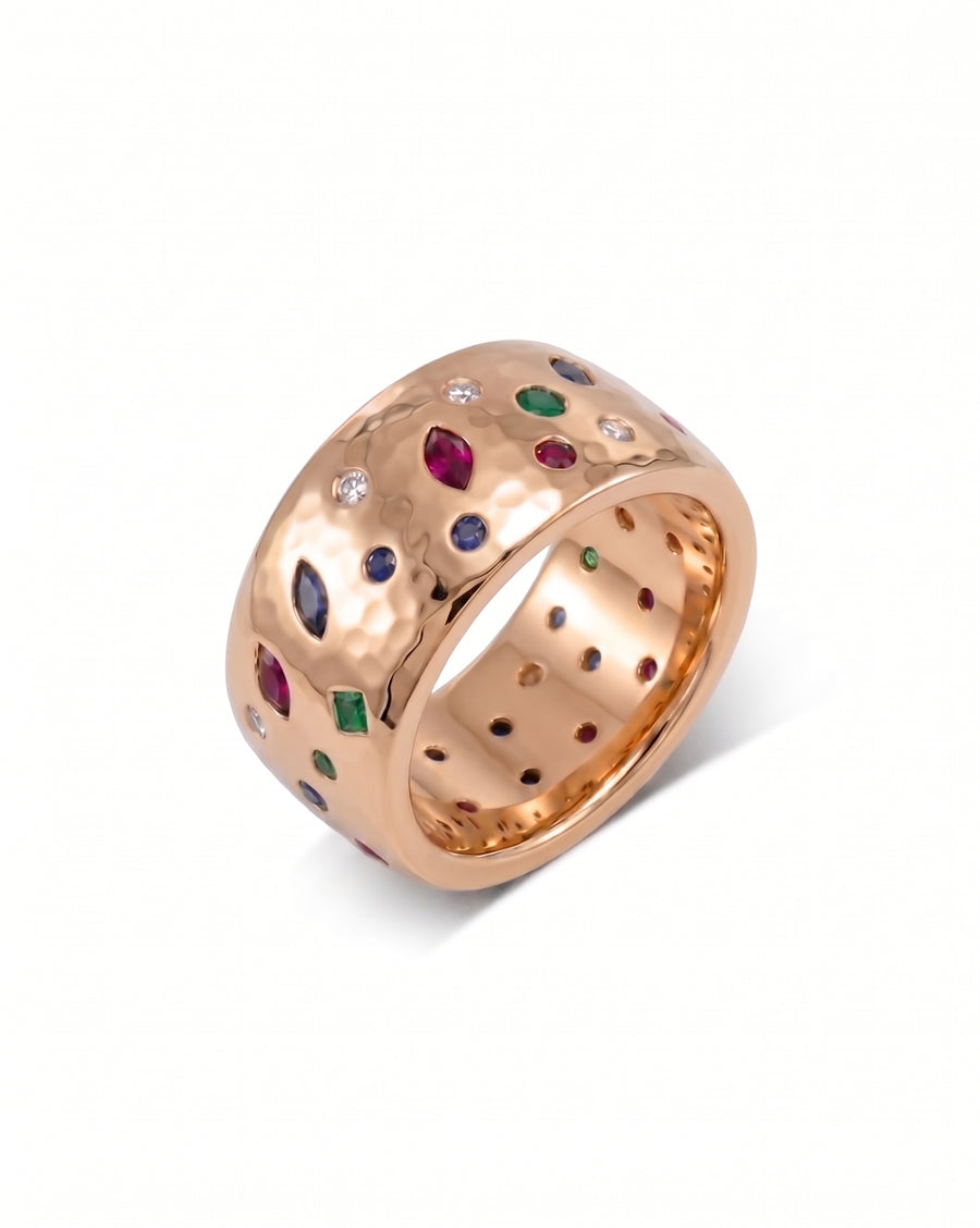 18ct rose gold wide hammered ring with scattered sapphire, emerald, ruby, and diamond gemstones.