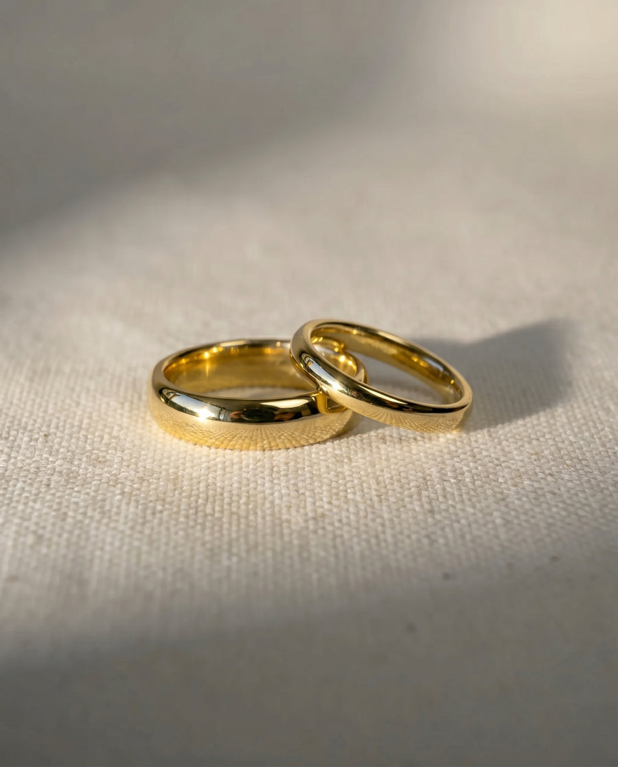 Two gold classic low court wedding rings on a light fabric.