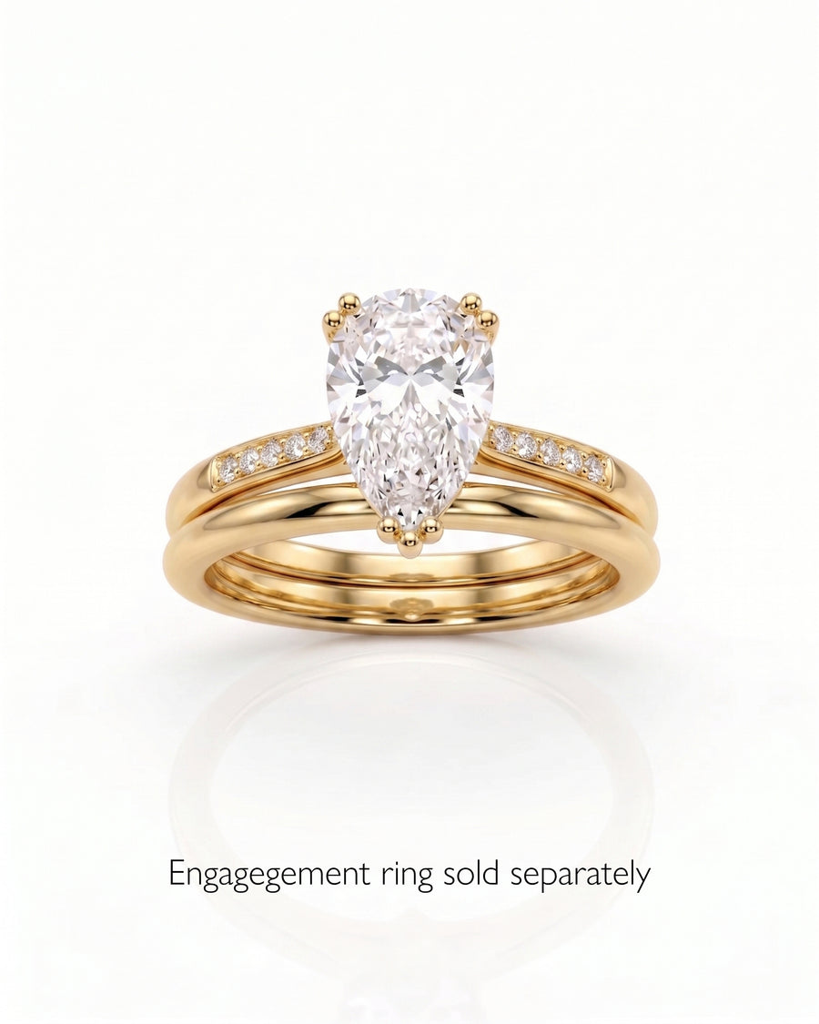 Gold wedding band with small diamonds, paired with a pear-cut diamond engagement ring.