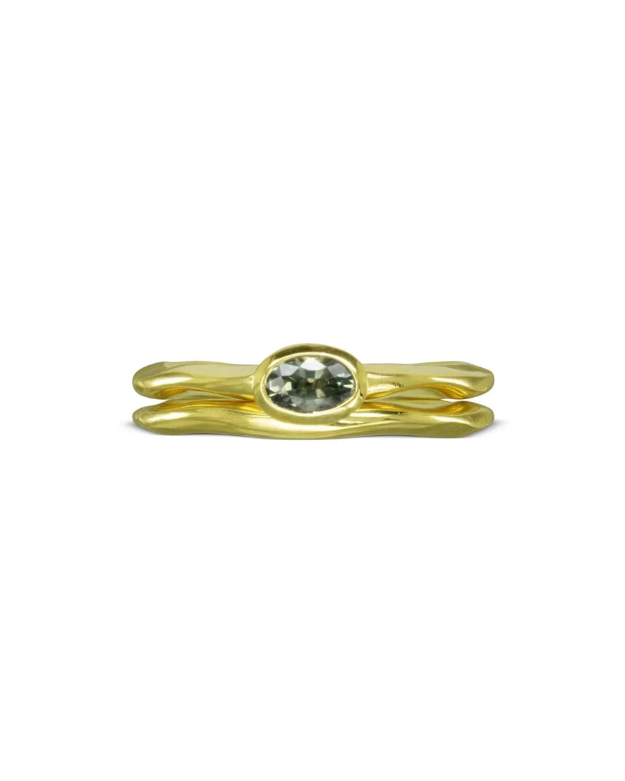Gold uneven wedding ring with an oval green gemstone.