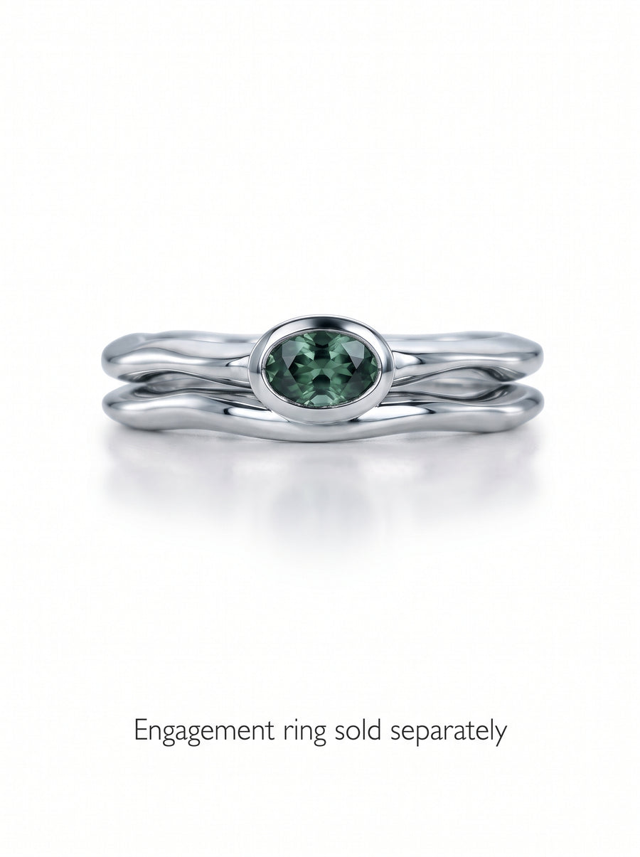 Silver wedding ring with an uneven, wavy band and a bezel-set oval green gemstone.
