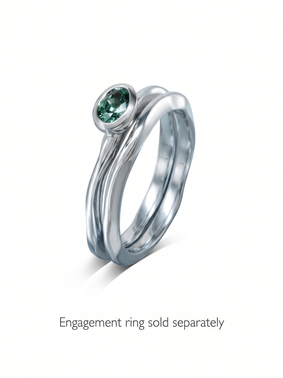 Dainty 2mm platinum wedding ring with an uneven, organic band design and a bezel-set oval green gemstone.