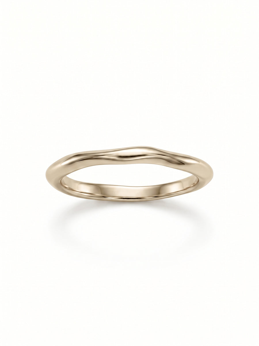 Dainty gold wedding ring with a smooth, uneven organic wave design on a white background.