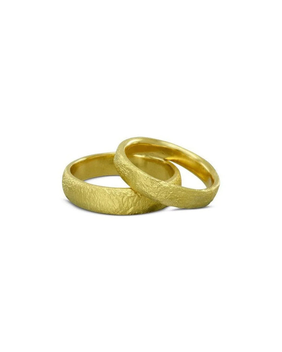 Textured yellow gold wedding bands with a rugged, organic finish on a white background