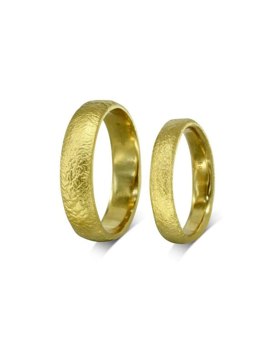 Textured gold wedding rings with organic, handcrafted design on white background