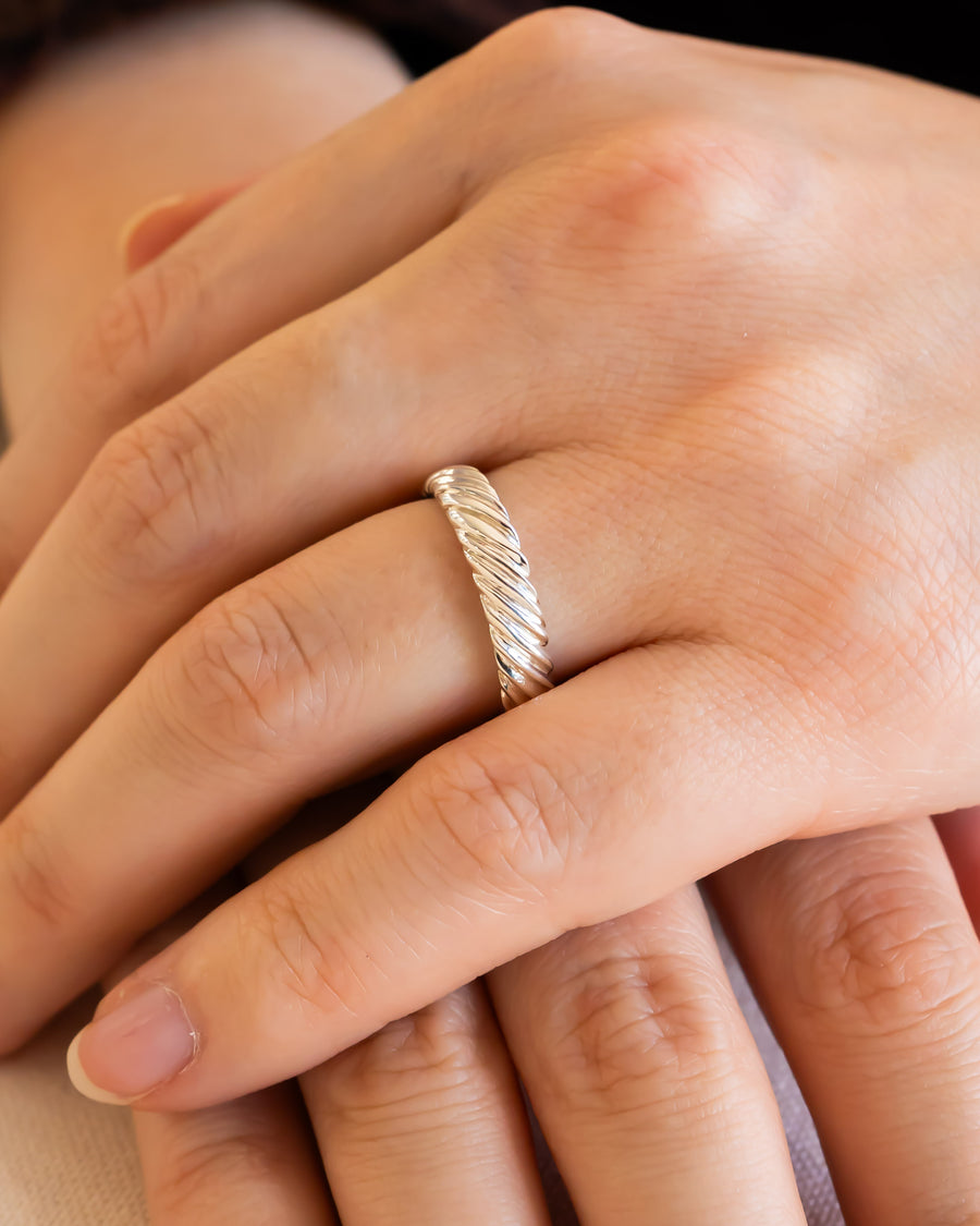 Silver twist wedding ring on a woman's finger.
