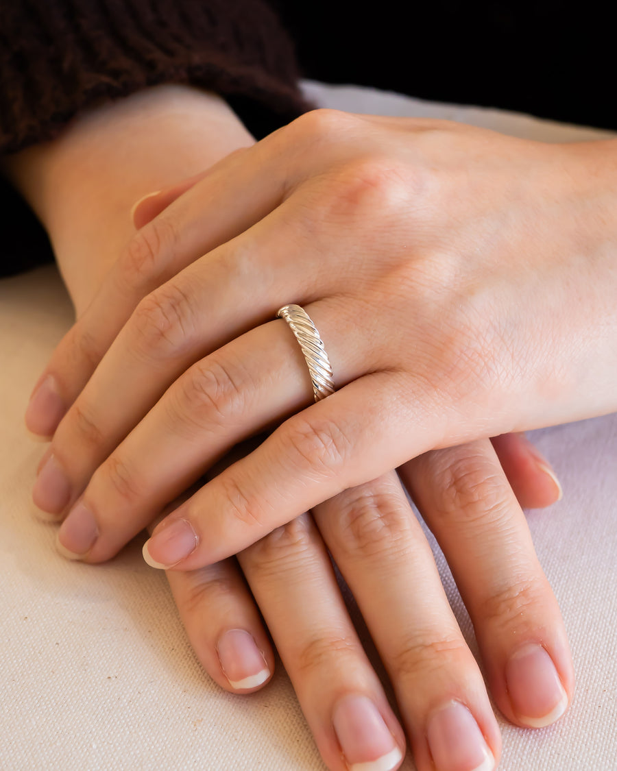 Silver twist wedding ring on a woman's finger.