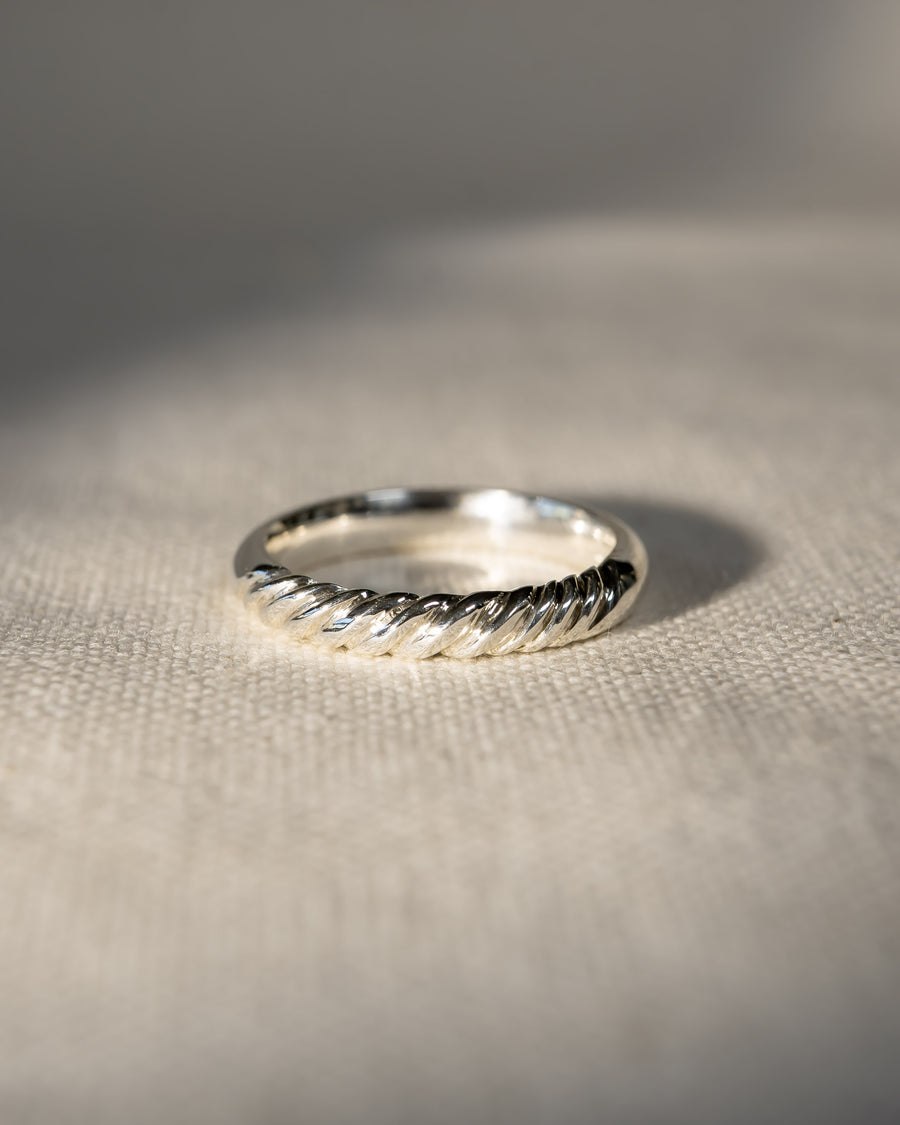 9ct white gold twist wedding ring on a light fabric surface.