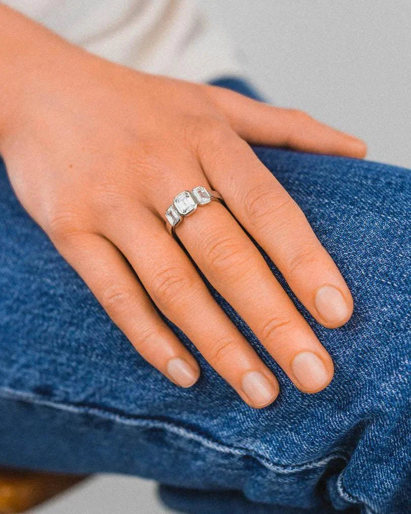 Silver ring with three clear rectangular gemstones on a hand.