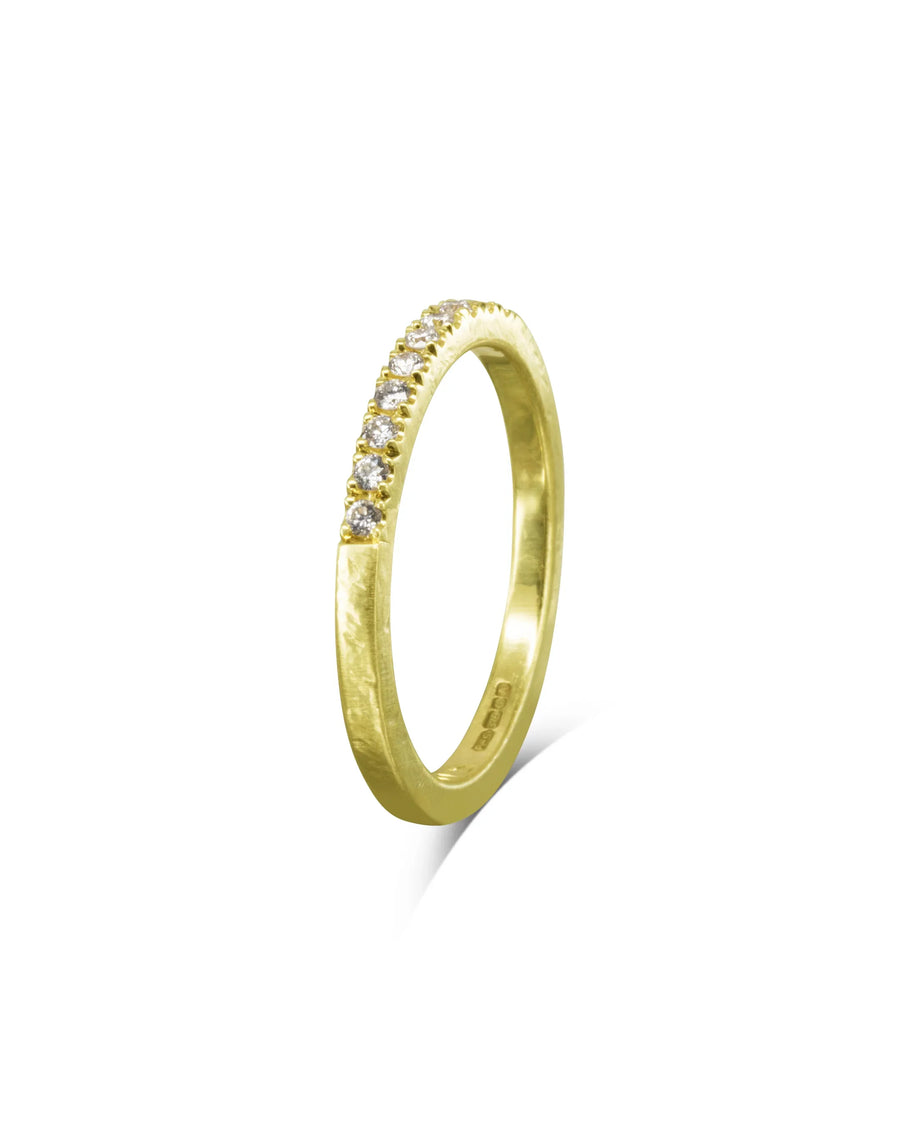 Handcrafted yellow gold ring with a row of sparkling diamonds on a white background